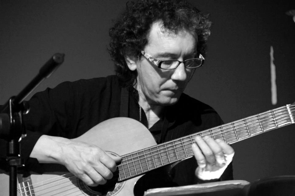 Primer plano de Miguel Anda tocando la guitarra en un escenario, en blanco y negro