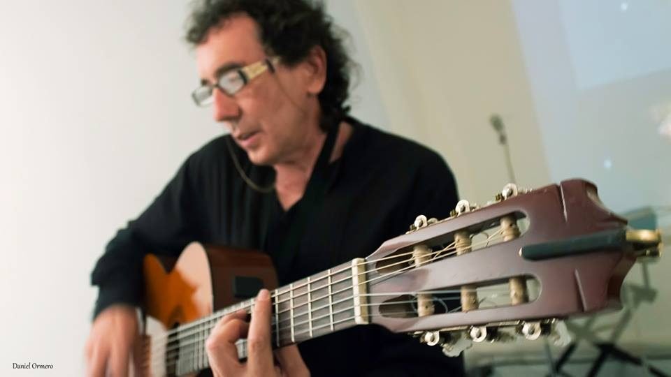 Miguel Anda tocando la guitarra clásica, en primer plano el clavijero del instrumento